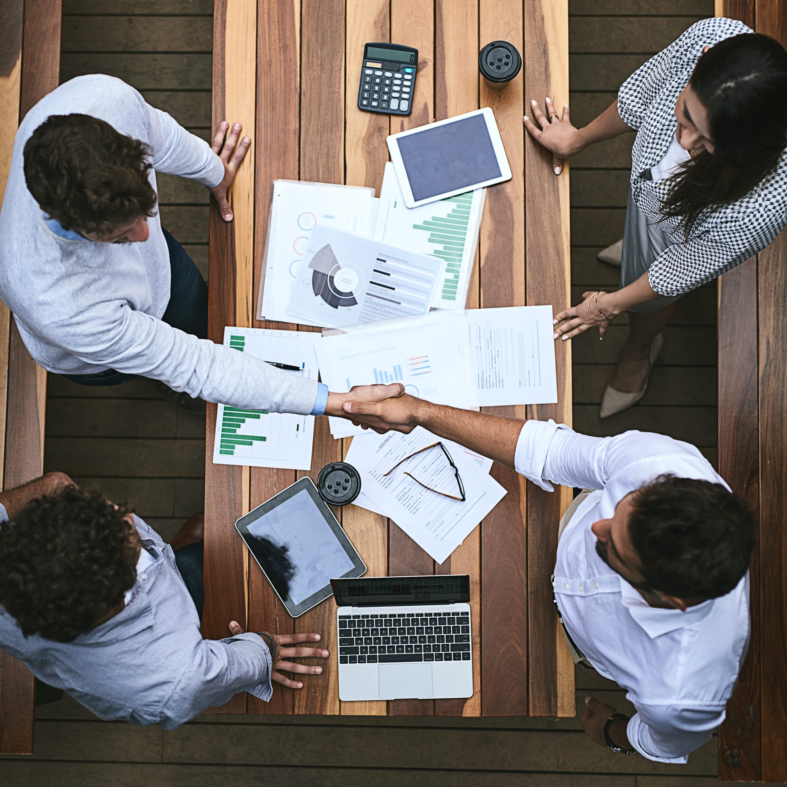 Accounting services team reviewing financial documents and shaking hands, symbolizing collaboration and accuracy in financial management.